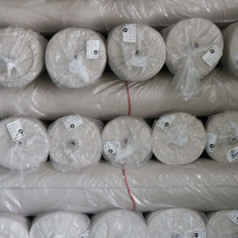A stack of plastic wrap rolls in a warehouse, with some rolls featuring lace fabric patterns