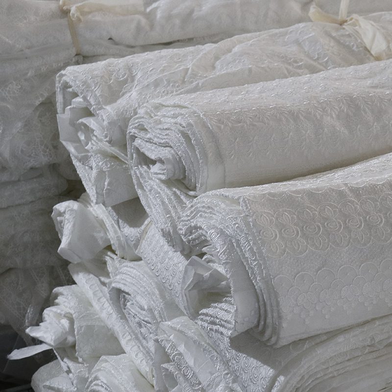 A stack of white sheets layered on top of each other, featuring delicate lace fabric along the edges