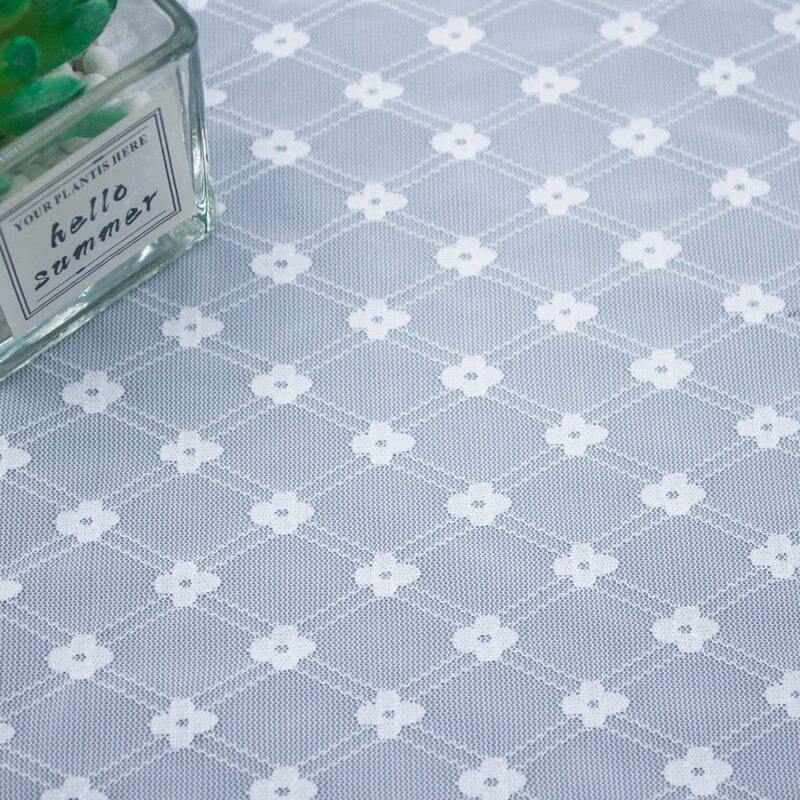 Detailed view of a white and gray patterned lace fabric, showcasing its delicate texture and design