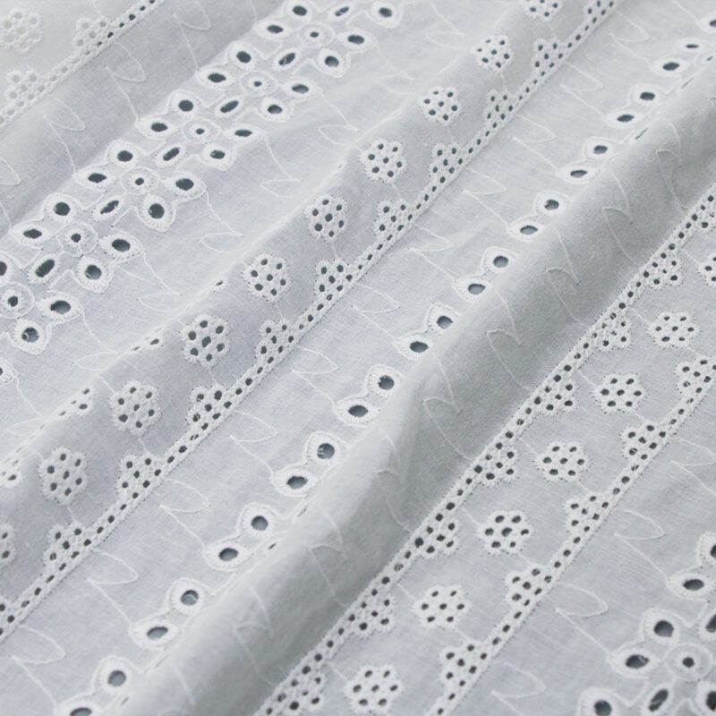 White cotton lace fabric featuring small holes and dots, creating a delicate and intricate pattern