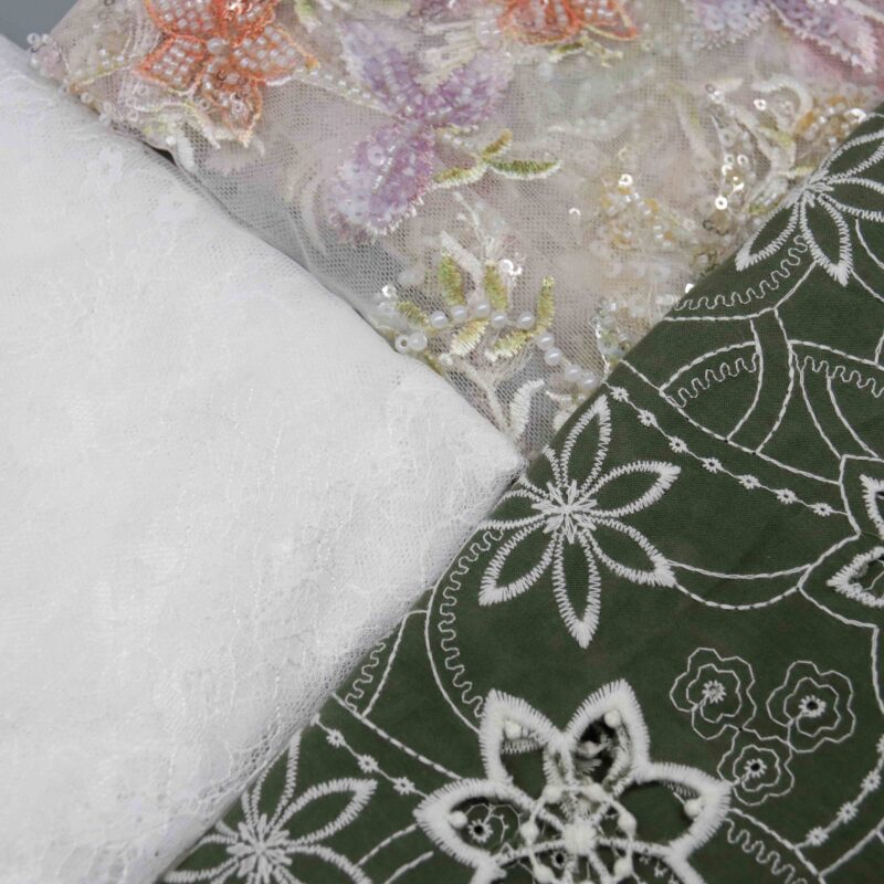 Three types of white and green lace fabric displayed together, showcasing intricate patterns and textures