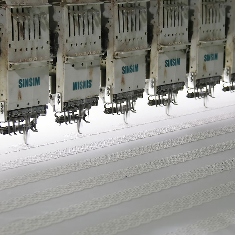 A fabric-making machine generating lace, illustrating the intricate design and production of lace material