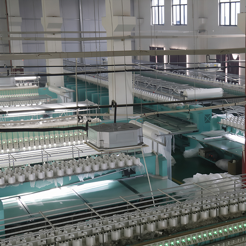 A lace fabric factory filled with machines, surrounded by lush greenery, showcasing a blend of industry and nature