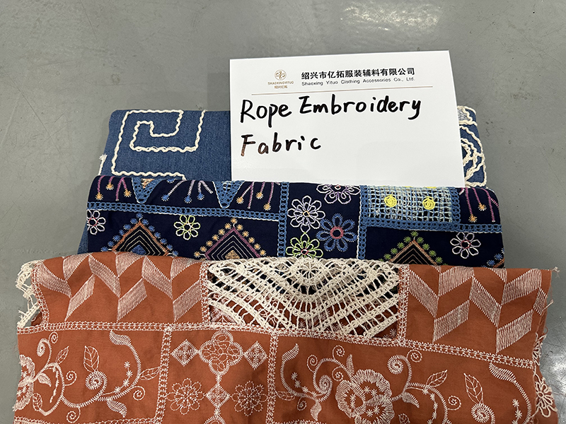 A pile of corded lace fabric samples with a visible label indicating the fabric type