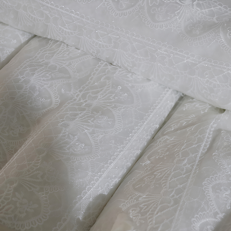 Close-up of a bed with white sheets featuring delicate lace fabric along the edges