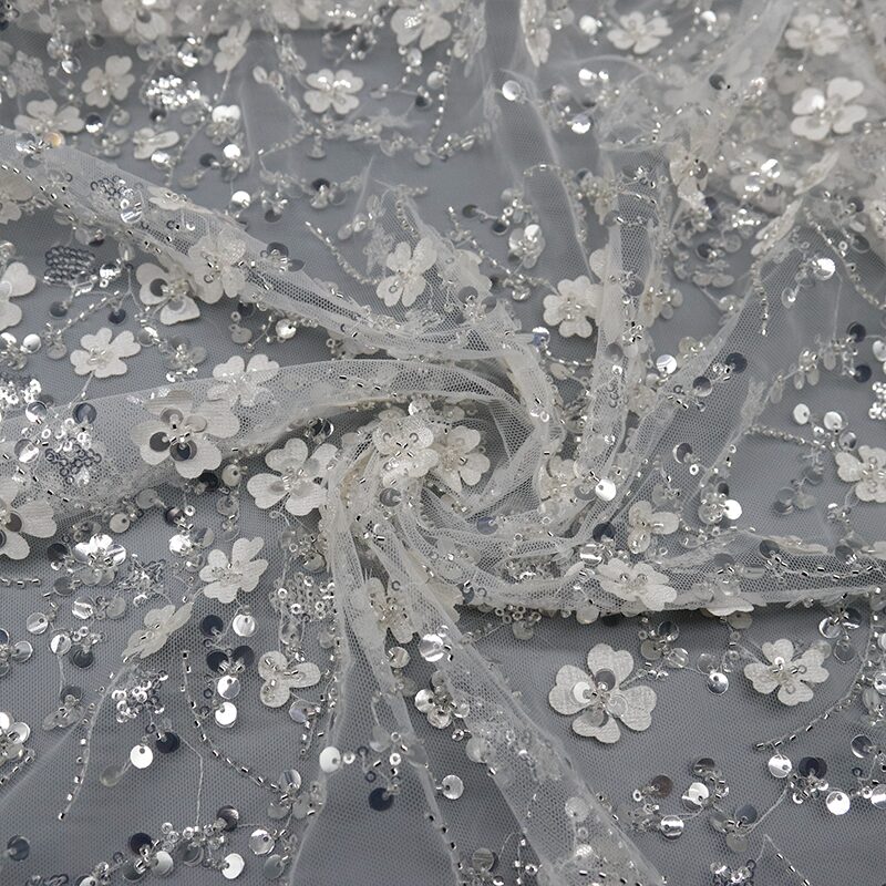 Close-up of white and silver sequinned lace fabric, showcasing intricate patterns and shimmering details