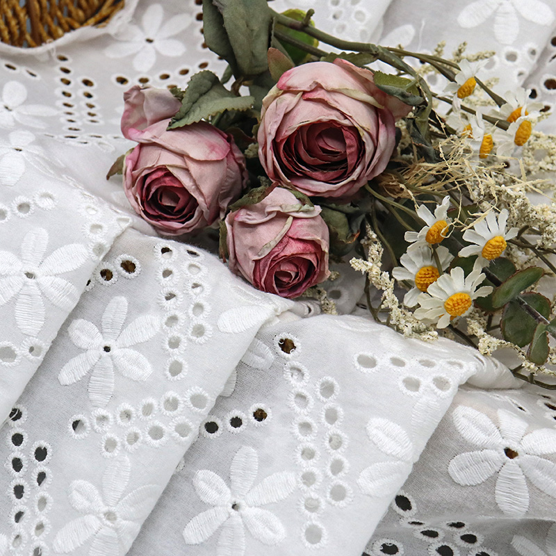 Delicate white cotton lace with floral embellishments, highlighting a refined and intricate design
