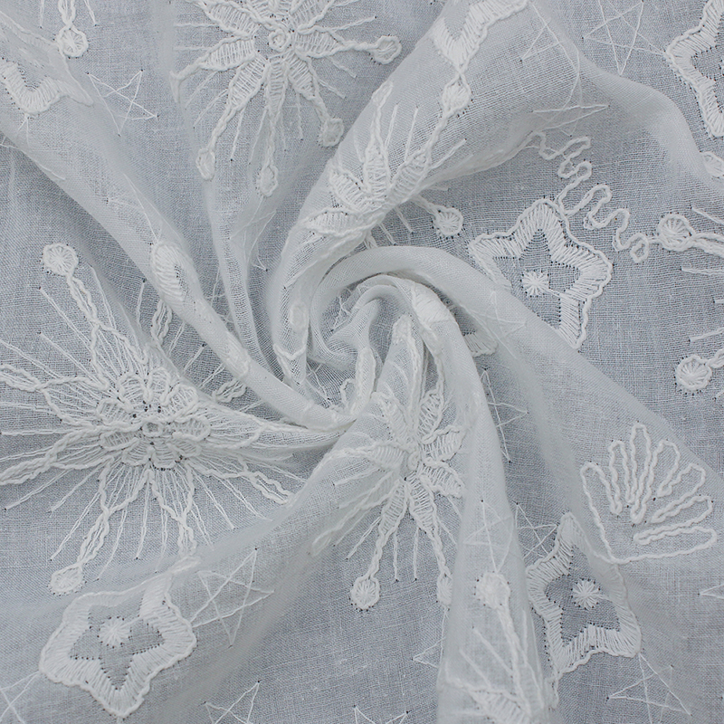 Delicate white embroidered lace fabric adorned with a floral pattern, made of cotton.