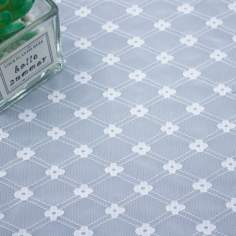 Detailed view of a white and gray patterned lace fabric, showcasing its delicate texture and design