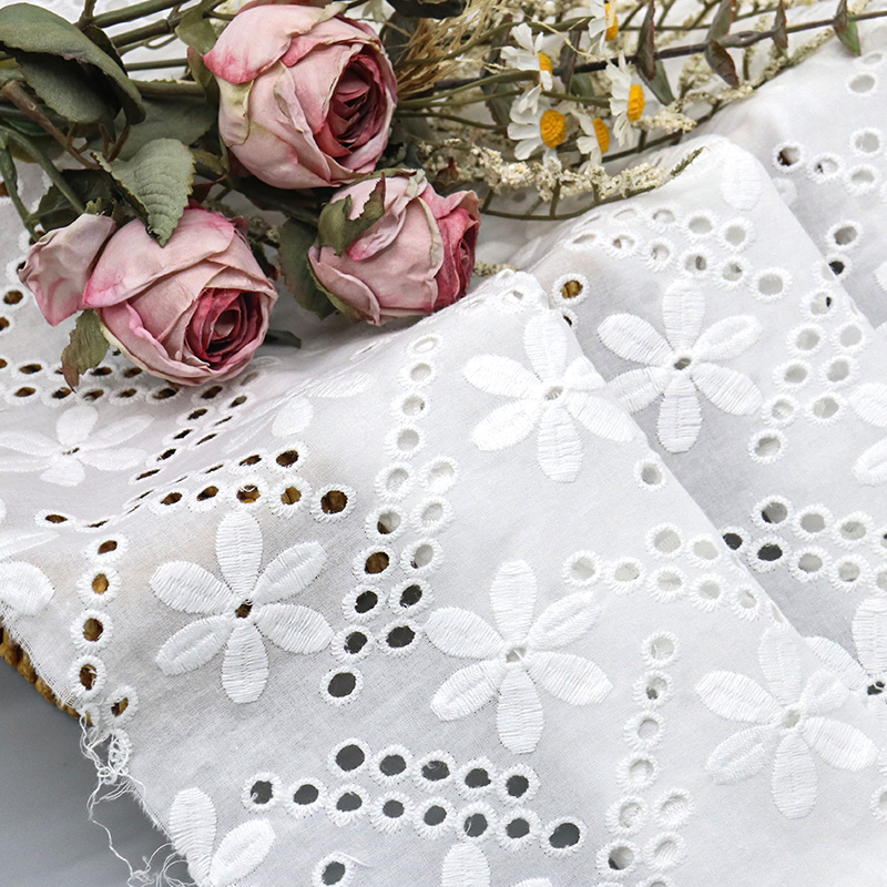 Elegant white lace fabric featuring floral designs, made of soft cotton for a delicate appearance