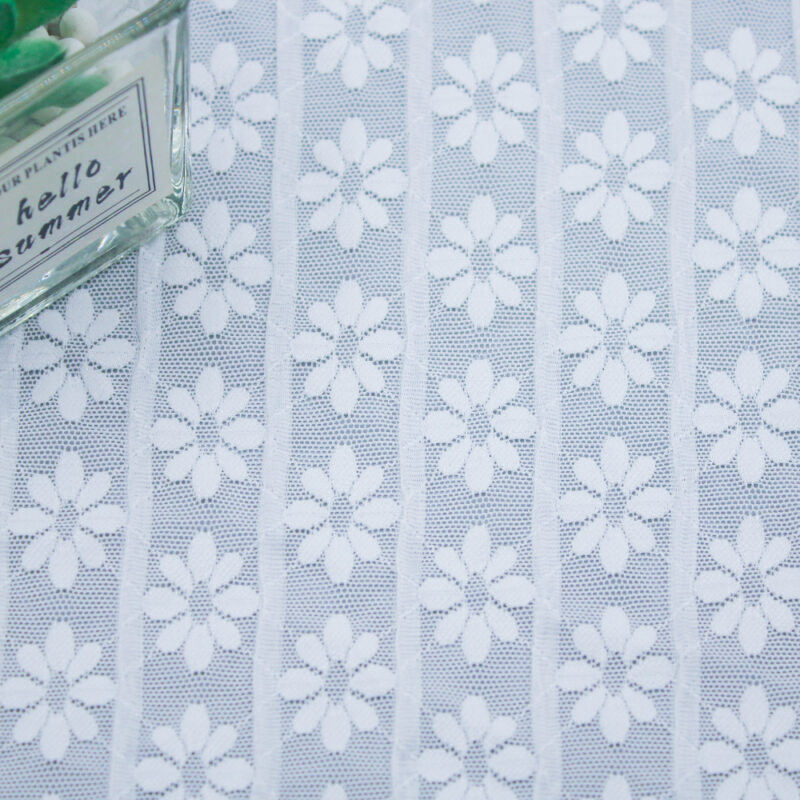 Elegant white lace fabric with floral designs, emphasizing its intricate patterns and delicate texture