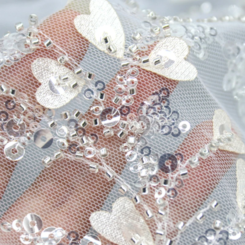Shimmering silver sequin fabric adorned with delicate white floral and leaf patterns