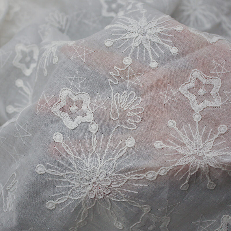 White fabric made of cotton, adorned with detailed embroidery