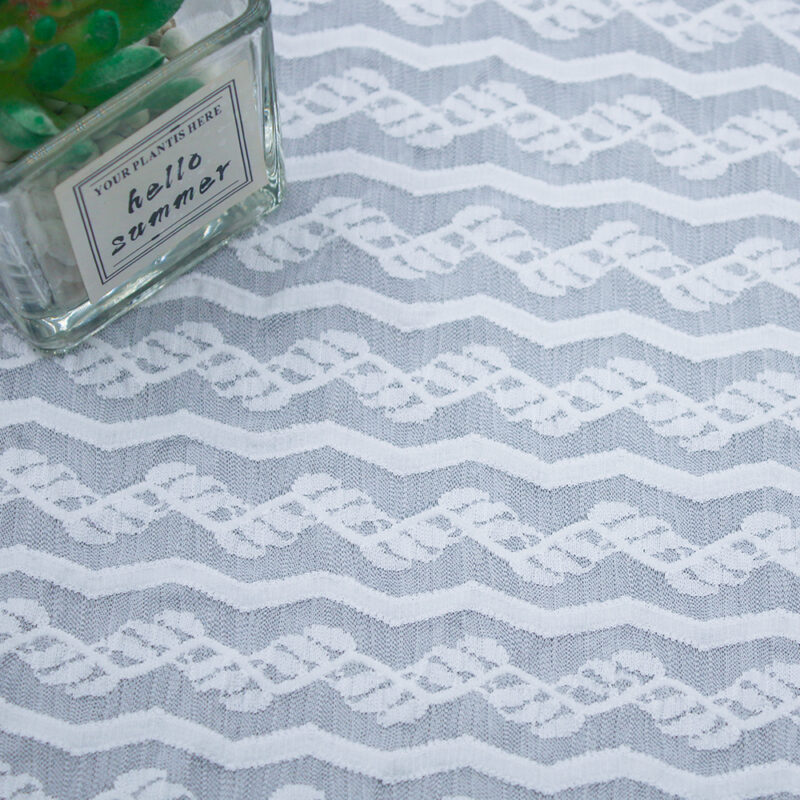 White lace fabric featuring a repeating pattern of blue and white designs