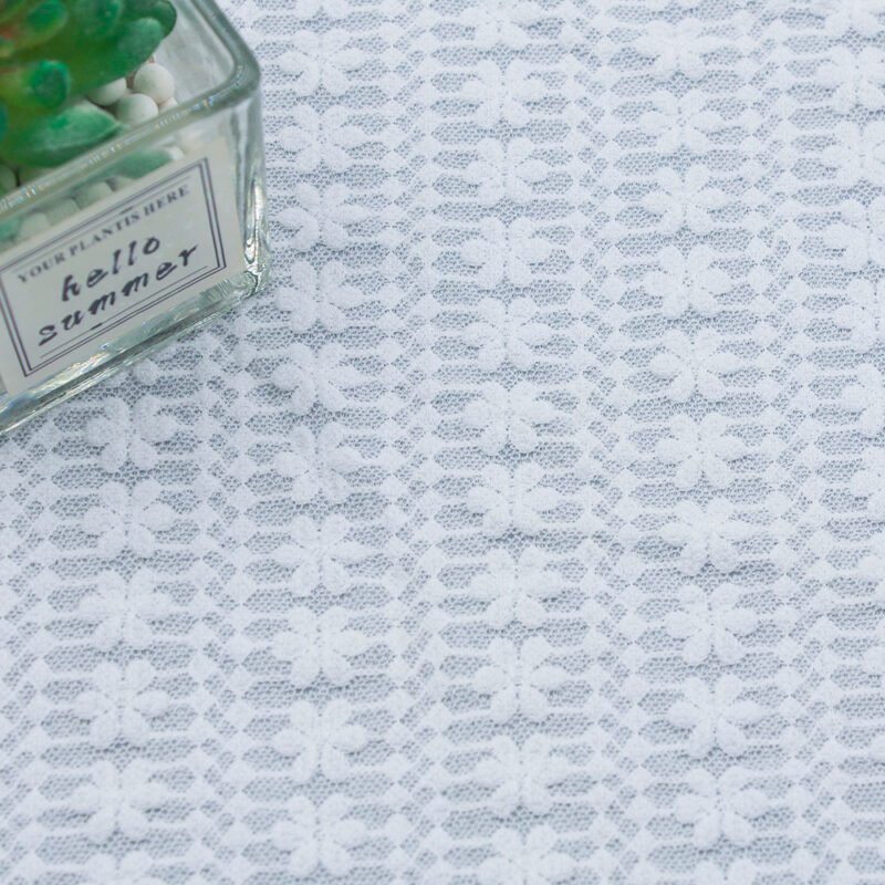 White lace fabric featuring floral patterns, showcasing intricate designs and delicate textures